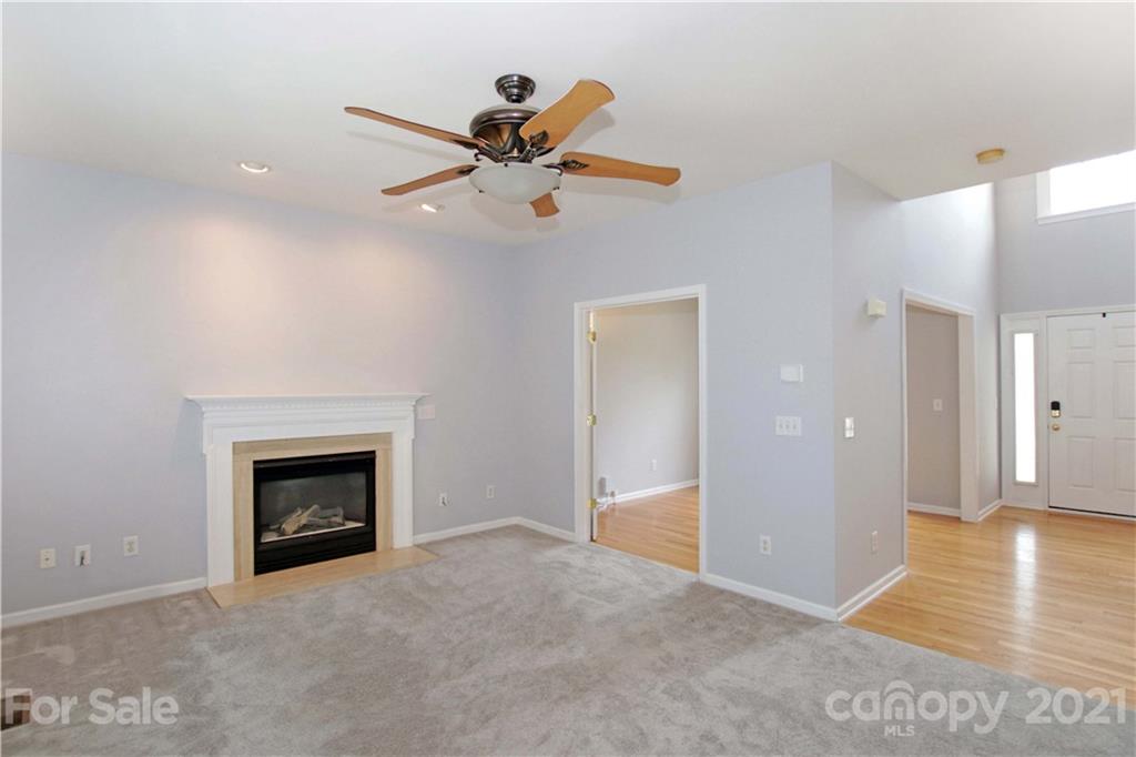 10402 Friarsgate Road Huntersville, NC 28078 - Photo 11 of 46 a view of an empty room and kitchen with fireplace ceiling fan