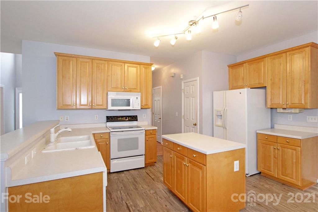 10402 Friarsgate Road Huntersville, NC 28078 - Photo 18 of 46 a kitchen with stainless steel appliances a stove a refrigerator a sink a oven with wooden cabinets and wooden floor