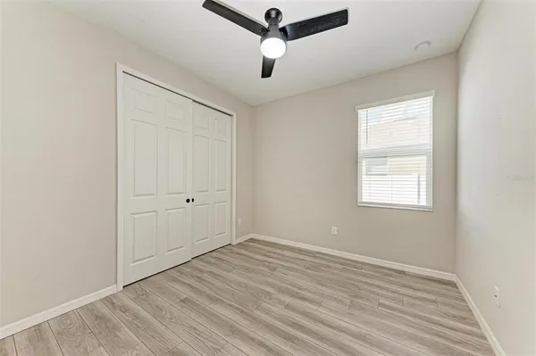 an empty room with a window and a ceiling fan