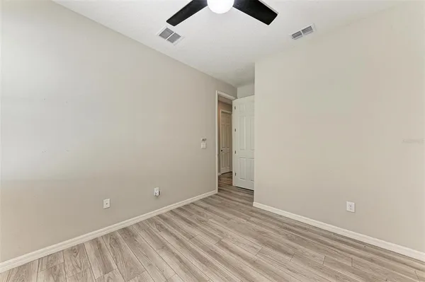 an empty room with ceiling fan and window