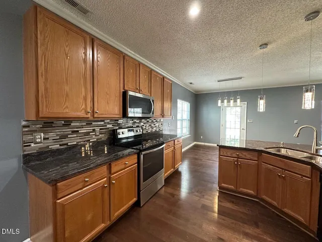 a kitchen with stainless steel appliances granite countertop wooden cabinets and a stove top oven