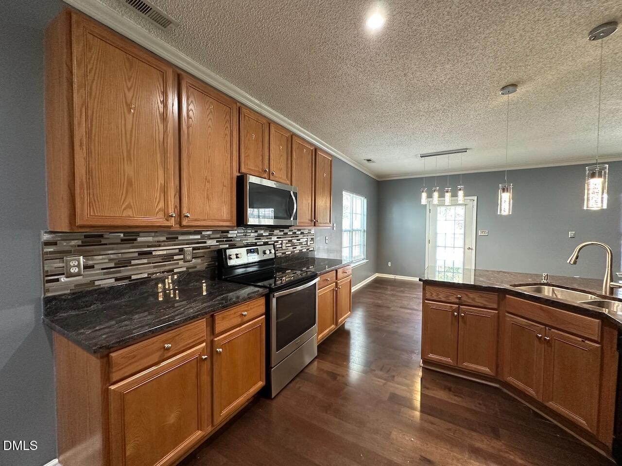 4617 Six Siblings Circle Raleigh, NC 27610 - Photo 12 of 35 a kitchen with stainless steel appliances granite countertop wooden cabinets and a stove top oven