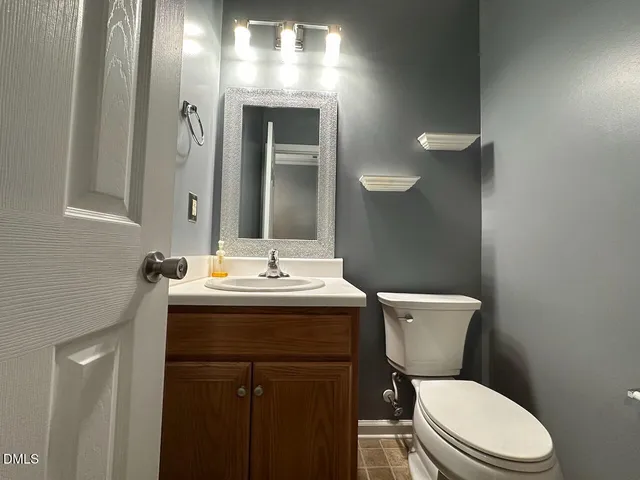 a bathroom with a toilet sink vanity and mirror