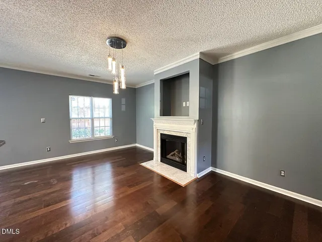 a view of an empty room with wooden floor fireplace and a window