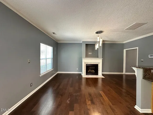 an empty room with wooden floor fireplace and windows