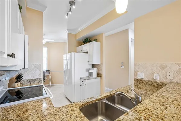 a kitchen with granite countertop white cabinets and white appliances