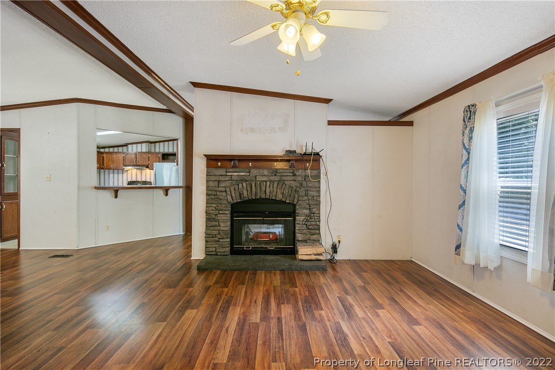 922 Magnolia Church Road Stedman, NC 28391 - Photo 12 of 49 an empty room with wooden floor a fireplace and windows