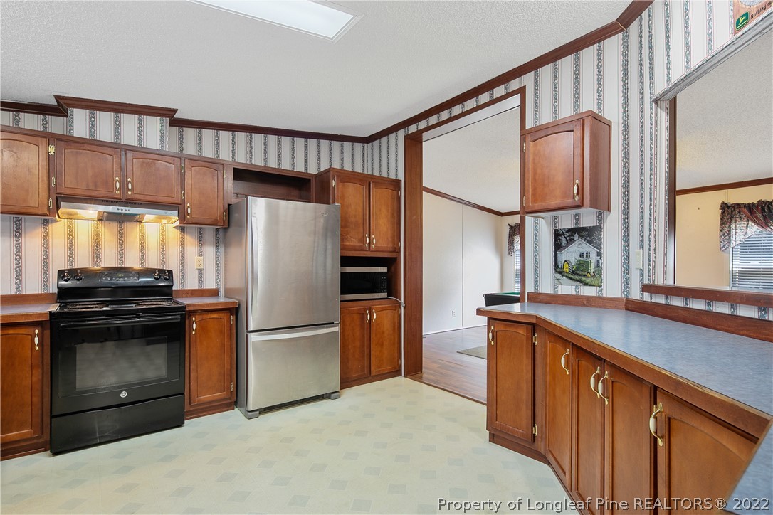 922 Magnolia Church Road Stedman, NC 28391 - Photo 16 of 49 a kitchen with stainless steel appliances granite countertop a refrigerator a stove and a sink with wooden floor