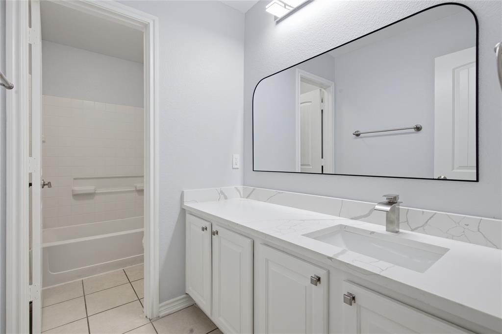 10001 Thurman Road Fort Worth, TX 76244 - Photo 31 of 40 Modern bathroom vanity featuring white cabinetry with square knobs, a rectangular undermount sink, and a single-handle chrome faucet