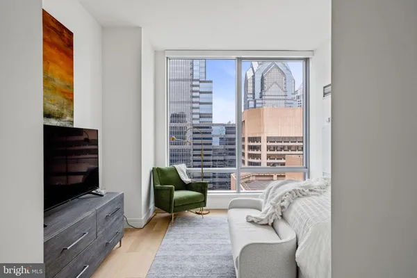 a living room with furniture a rug a lamp and a large window