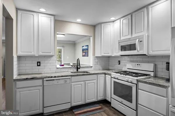 a kitchen with granite countertop white cabinets and stainless steel appliances