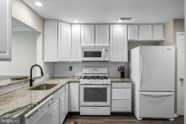 a kitchen with white cabinets and white appliances