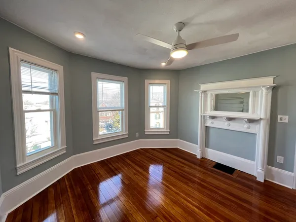 a view of an empty room with chandelier and wooden floor