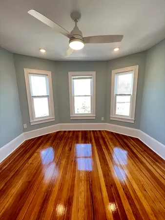 a view of an empty room with wooden floor and window
