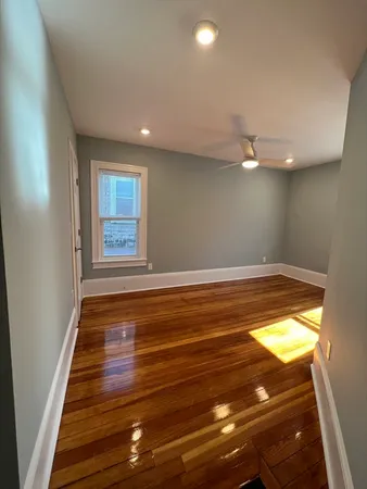 a view of empty room with window and wooden floor