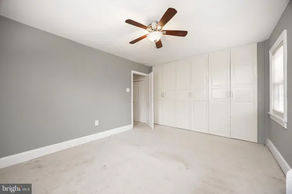 an empty room with ceiling fan and window