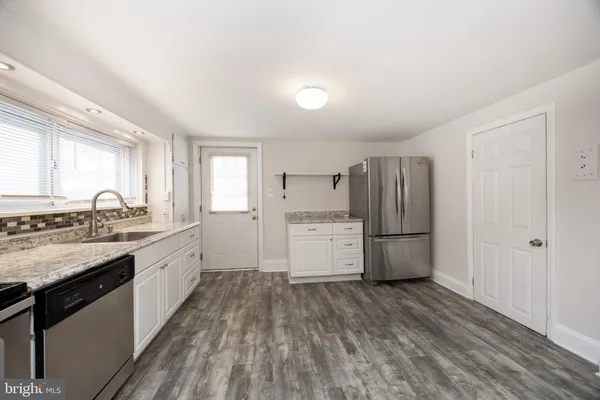 a kitchen with a white cabinets and wooden floor