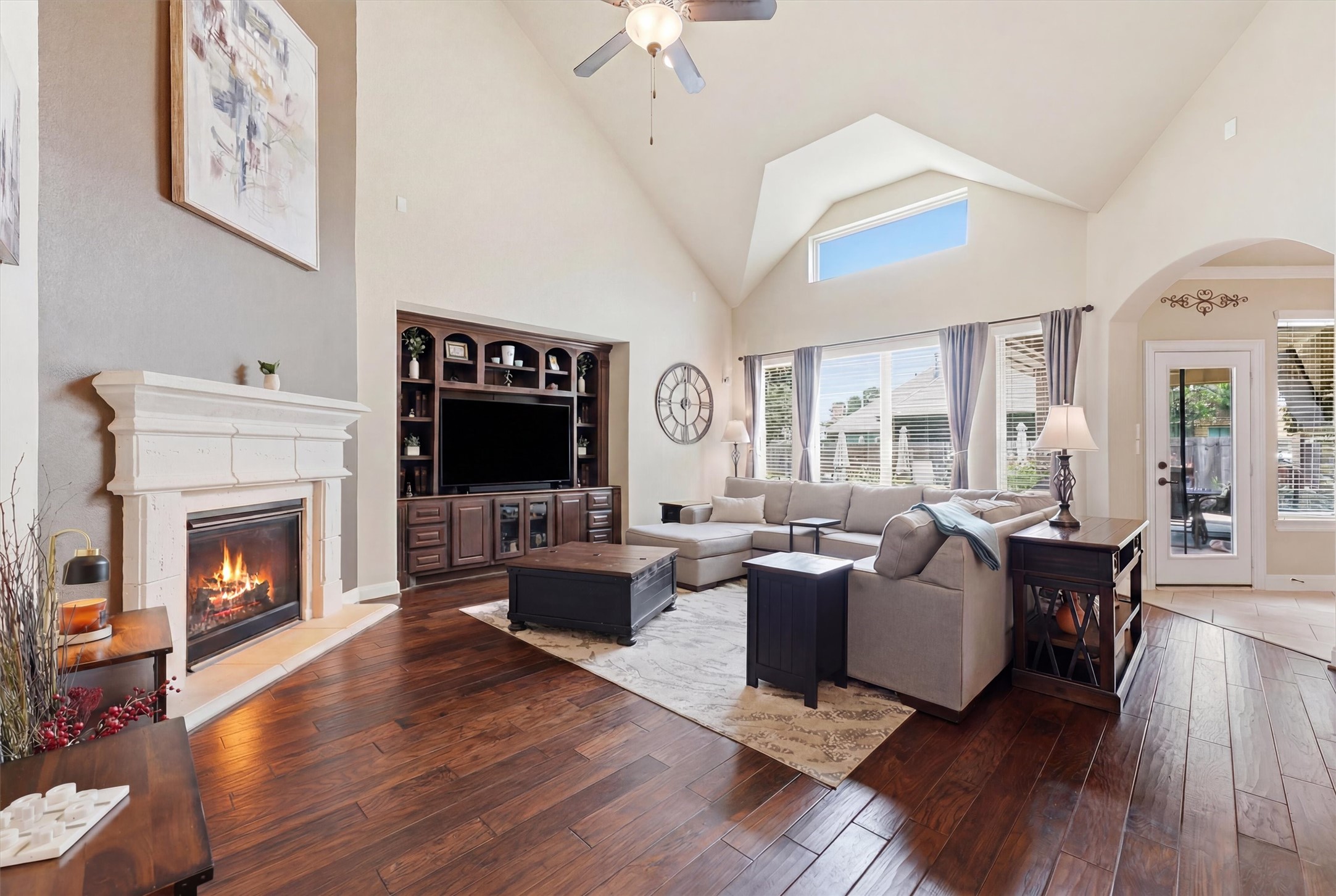 17710 Rough River Court Humble, TX 77346 - Photo 10 of 38 This spacious living room features high vaulted ceilings, a cozy fireplace, and abundant natural light from large windows. The elegant hardwood floors complement the neutral decor, creating a warm and inviting atmosphere.