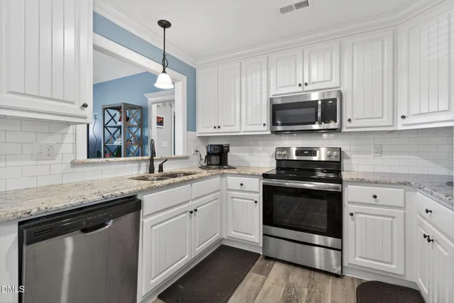 a kitchen with granite countertop white cabinets white stainless steel appliances and a sink
