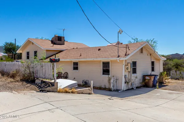 a view of a white house with lawn chairs under an umbrella