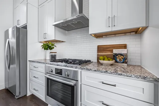 a kitchen with stainless steel appliances granite countertop white cabinets and a stove