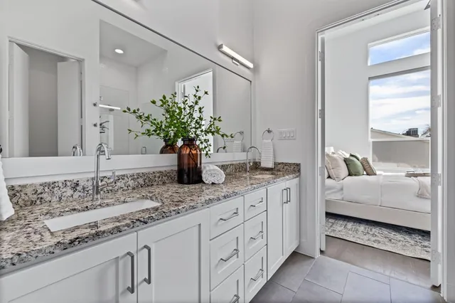 a spacious bathroom with a granite countertop sink a mirror and a shower