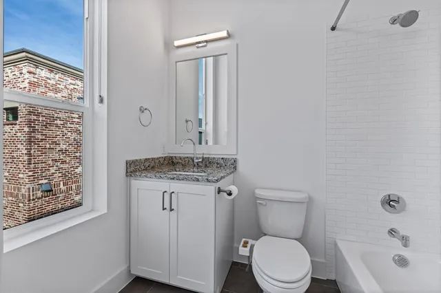 a bathroom with a granite countertop toilet and a sink