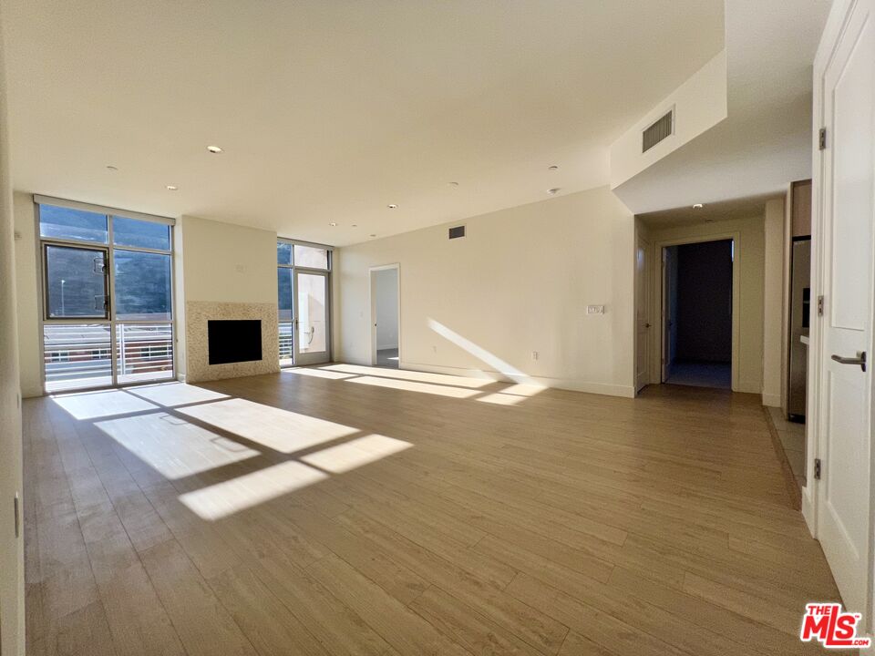 11715 Bellagio Road, Unit 305 Los Angeles, CA 90049 - Photo 3 of 25 a view of an empty room with wooden floor and a window