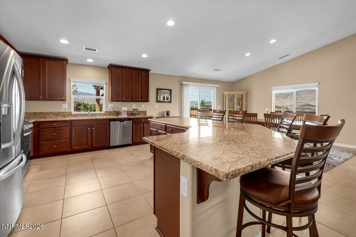 104 Bethpage Road Dayton, NV 89403 - Photo 14 of 65 a kitchen with stainless steel appliances granite countertop a table chairs sink refrigerator and cabinets