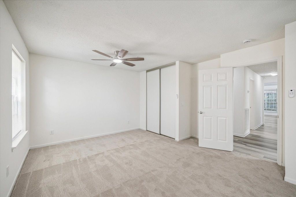 143 West Village Knoll Circle Spring, TX 77381 - Photo 16 of 27 This view showcases the fresh paint, new carpet, and large closet with sliding doors. The room is brightened by natural light from the window and features a modern ceiling fan. Conveniently located off the main hallway, it offers easy access to the rest of the home.