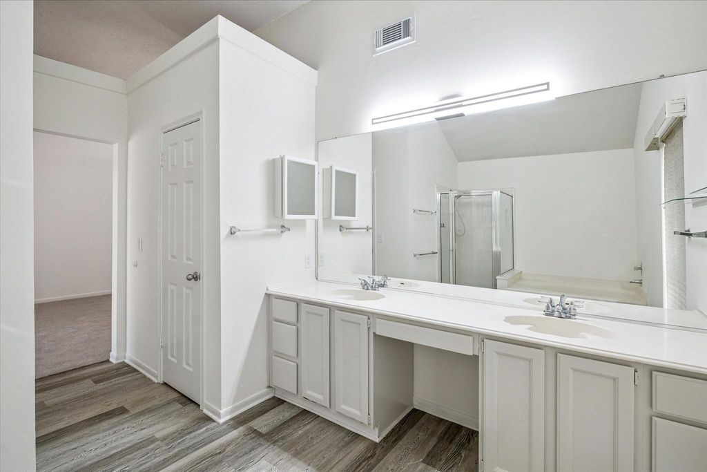 143 West Village Knoll Circle Spring, TX 77381 - Photo 22 of 27 This perspective highlights the expansive dual vanity with abundant storage and a large wall mirror. The layout flows seamlessly to the soaking tub and separate shower, creating a bright and functional retreat.