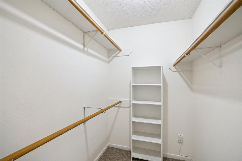 143 West Village Knoll Circle Spring, TX 77381 - Photo 23 of 27 Spacious walk-in closet in the primary suite featuring dual hanging rods for ample clothing storage and built-in shelving for organized accessories or folded items. A perfect blend of functionality and convenience!