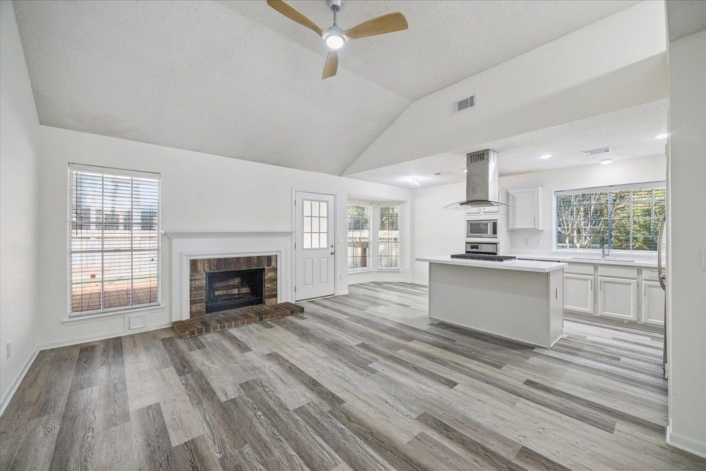 143 West Village Knoll Circle Spring, TX 77381 - Photo 3 of 27 Step into the spacious living room where new flooring, a cozy fireplace, and abundant natural light combine to create a comfortable and inviting gathering space. This room serves as the heart of the home, perfect for relaxing evenings or entertaining guests.