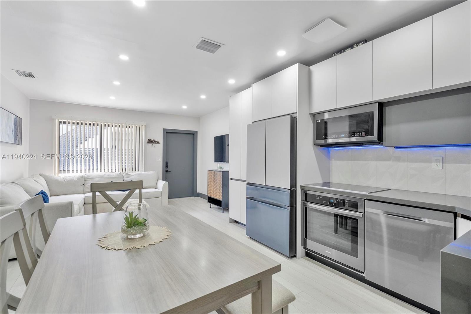 100 Northeast 71st Street, Unit 100 Miami, FL 33138 - Photo 1 of 15 a kitchen with stainless steel appliances a stove a refrigerator a sink a dining table and chairs
