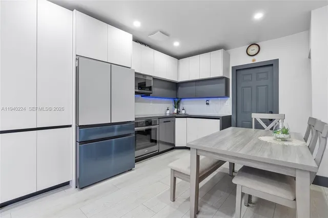 a kitchen with a table chairs refrigerator and microwave