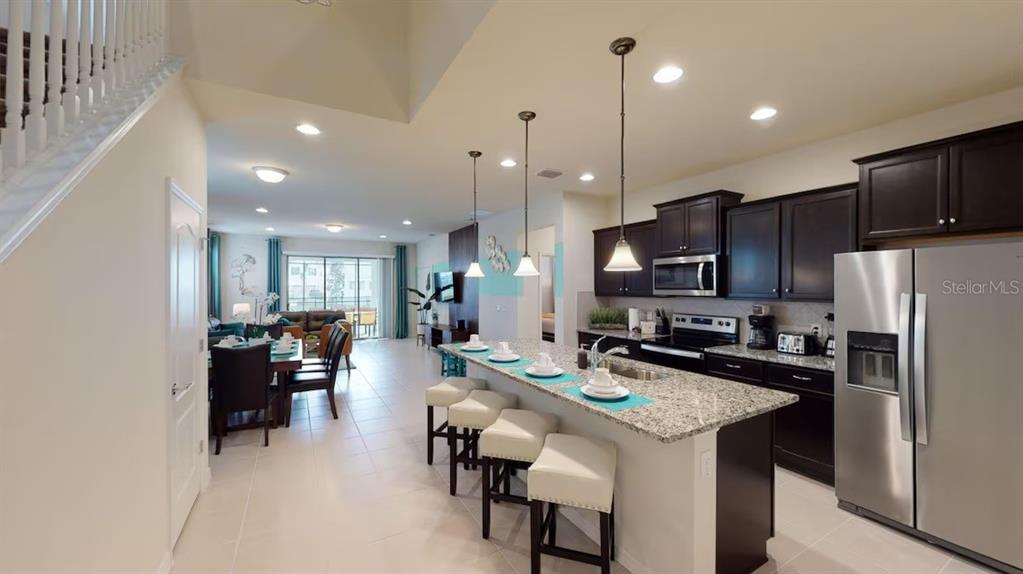2479 Dubai Street Kissimmee, FL 34747 - Photo 13 of 70 a kitchen with stainless steel appliances kitchen island granite countertop a refrigerator a stove a sink a dining table and chairs with wooden floor