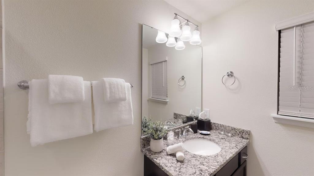 2479 Dubai Street Kissimmee, FL 34747 - Photo 30 of 70 a bathroom with a granite countertop sink a mirror and a shower