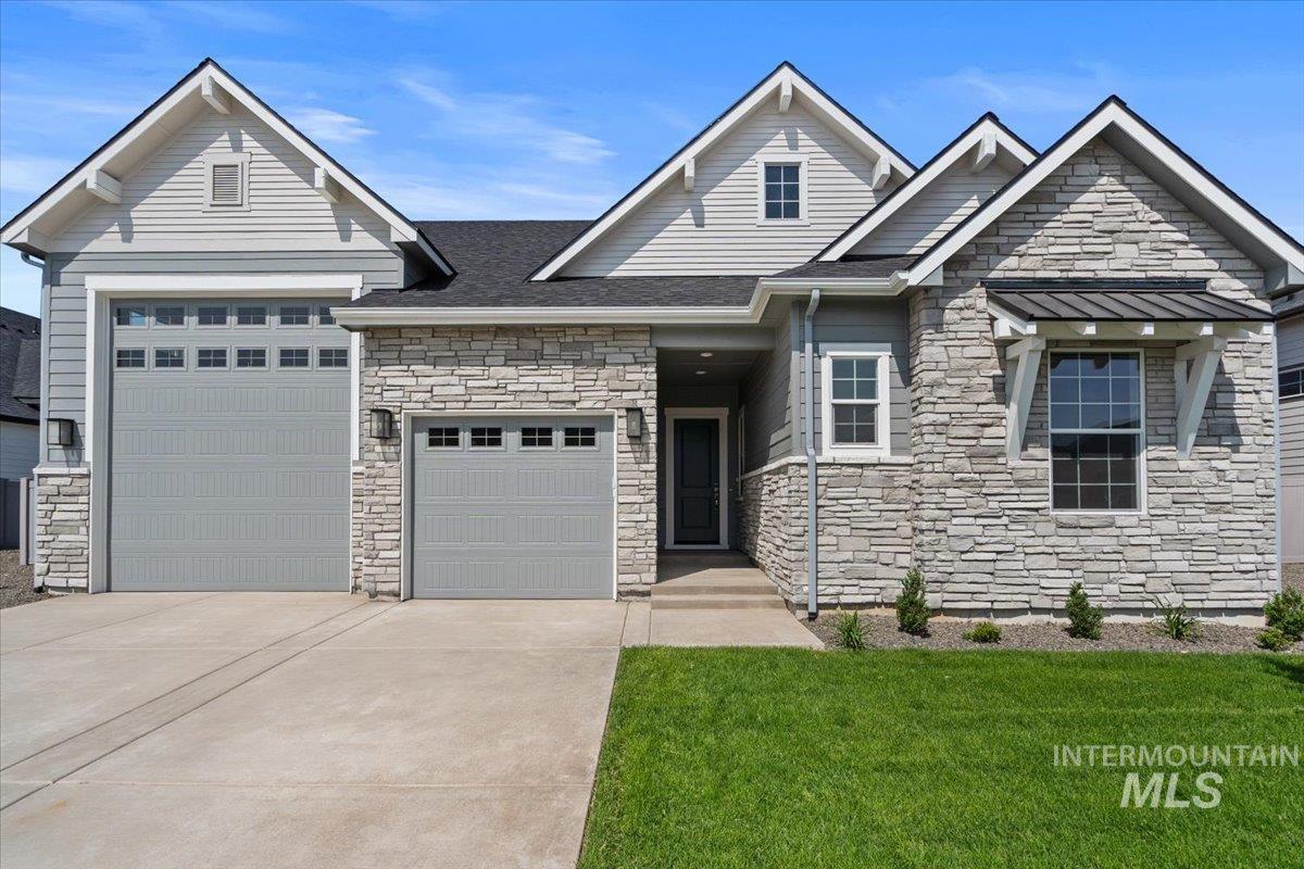 View of front of house with a garage, driveway, stone siding, and a front lawn