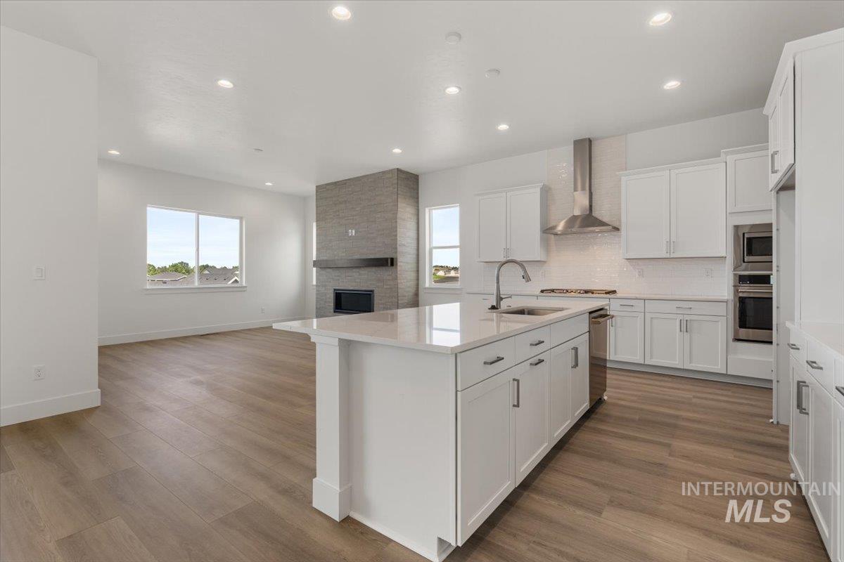 929 North Falling Water Way Eagle, ID 83616 - Photo 43 of 43 Kitchen featuring white cabinets, open floor plan, backsplash, wall chimney range hood, and recessed lighting