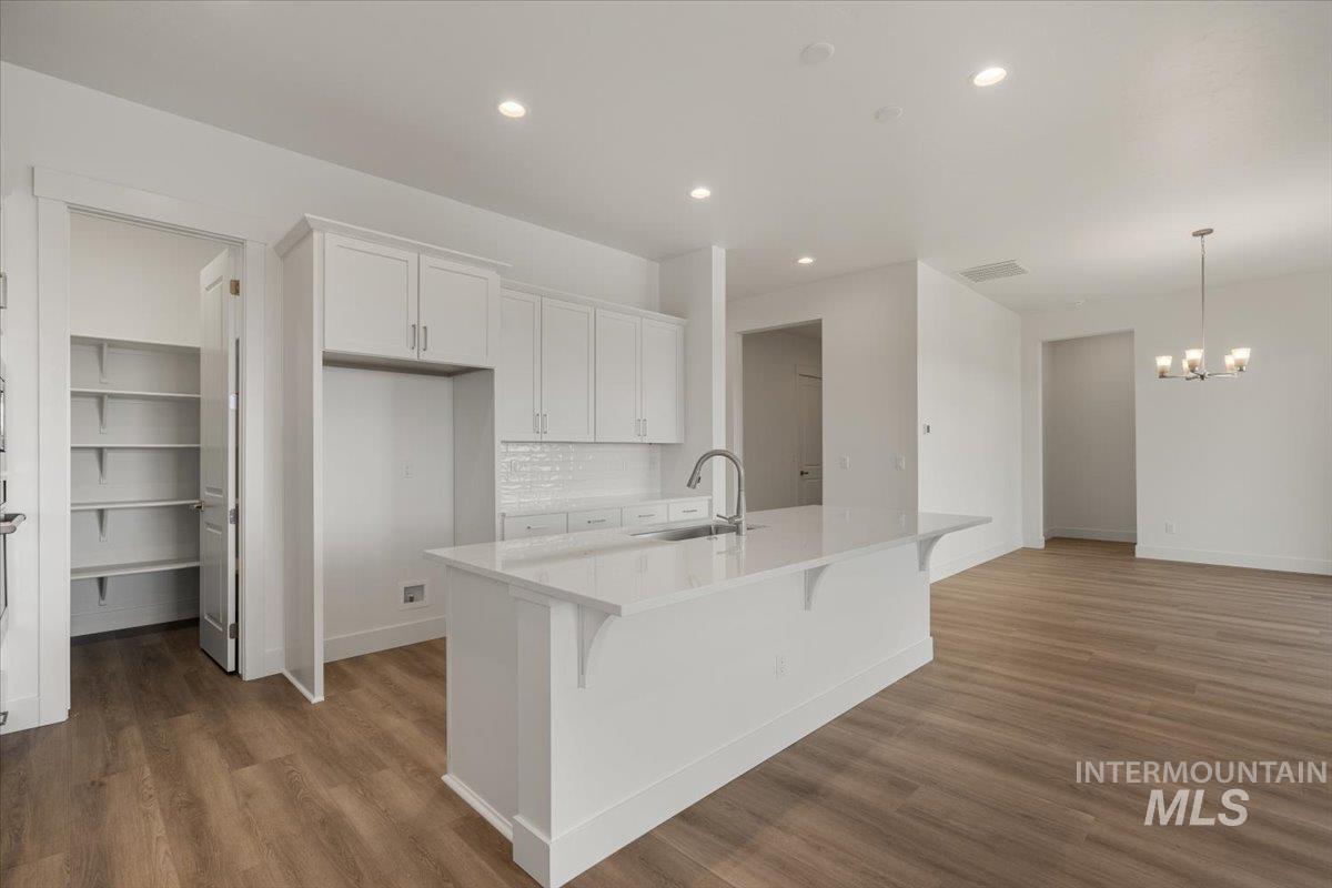 929 North Falling Water Way Eagle, ID 83616 - Photo 19 of 43 Kitchen featuring recessed lighting, white cabinetry, tasteful backsplash, a breakfast bar, and dark wood-style floors