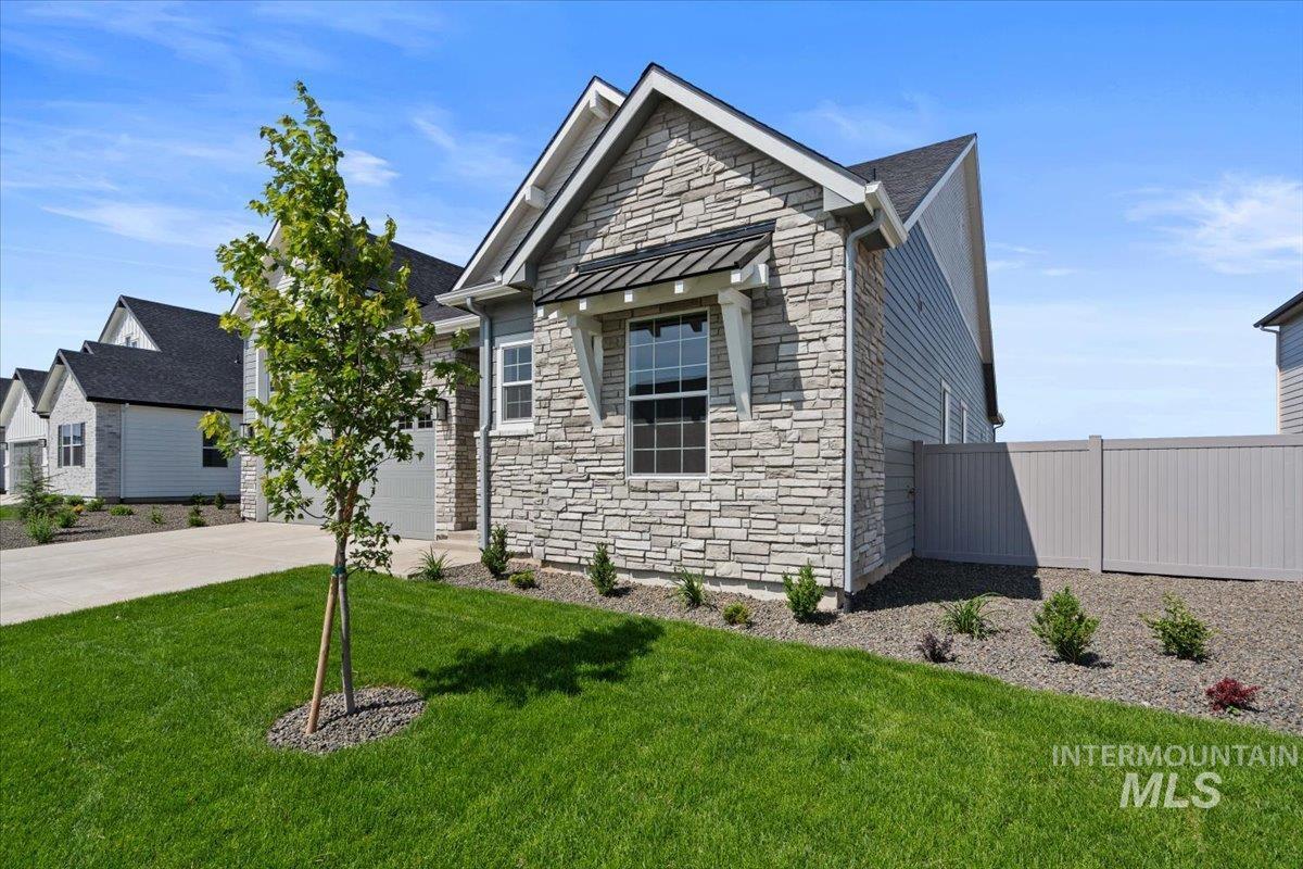 929 North Falling Water Way Eagle, ID 83616 - Photo 2 of 43 View of front facade featuring stone siding, driveway, a standing seam roof, a garage, and a metal roof