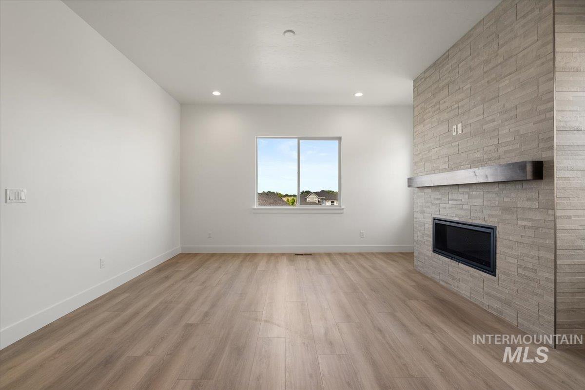 929 North Falling Water Way Eagle, ID 83616 - Photo 23 of 43 Unfurnished living room with light wood finished floors, a stone fireplace, and recessed lighting