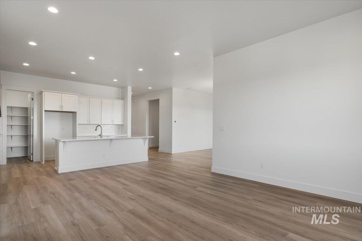 929 North Falling Water Way Eagle, ID 83616 - Photo 25 of 43 Kitchen featuring a breakfast bar area, a center island with sink, light wood finished floors, recessed lighting, and decorative backsplash