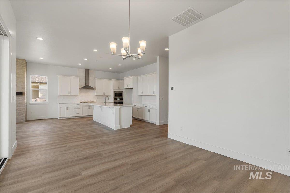 929 North Falling Water Way Eagle, ID 83616 - Photo 28 of 43 Kitchen with white cabinetry, hanging light fixtures, a center island with sink, a kitchen breakfast bar, and light wood-type flooring