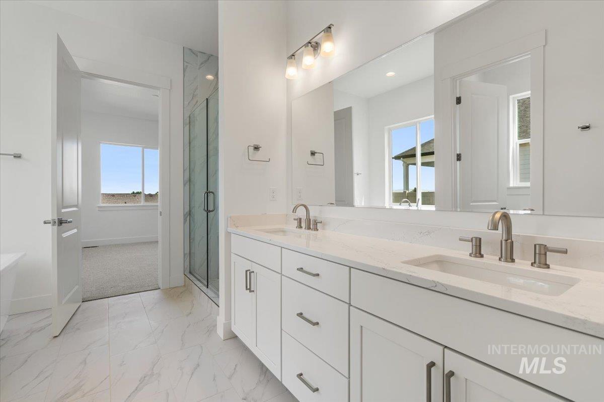 929 North Falling Water Way Eagle, ID 83616 - Photo 32 of 43 Bathroom featuring a marble finish shower, double vanity, light marble finish floors, and plenty of natural light