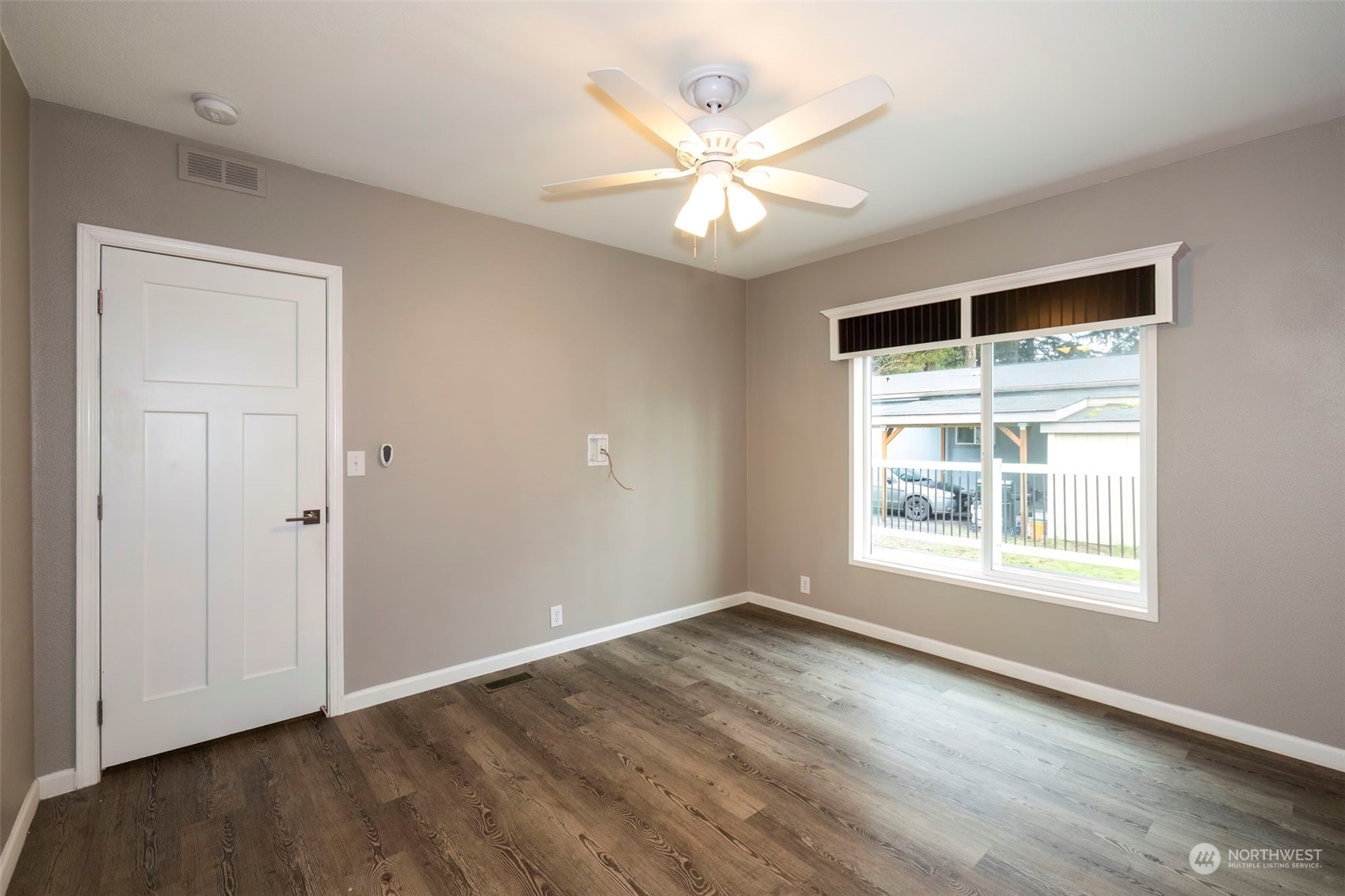 17340 Sargent Road Southwest, Unit 24 Rochester, WA 98579 - Photo 19 of 26 an empty room with wooden floor chandelier fan and windows