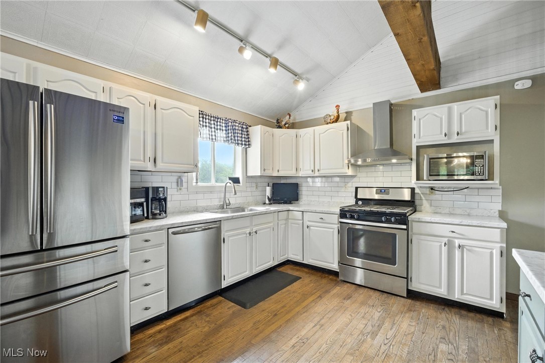 1371 Spider Ridge Road Parkersburg, WV 26104 - Photo 12 of 48 Kitchen featuring stainless steel appliances, vaulted ceiling, wall chimney range hood, dark wood-type flooring, and light countertops