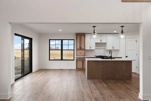 a kitchen with stainless steel appliances granite countertop a sink stove a refrigerator and white cabinets with wooden floor