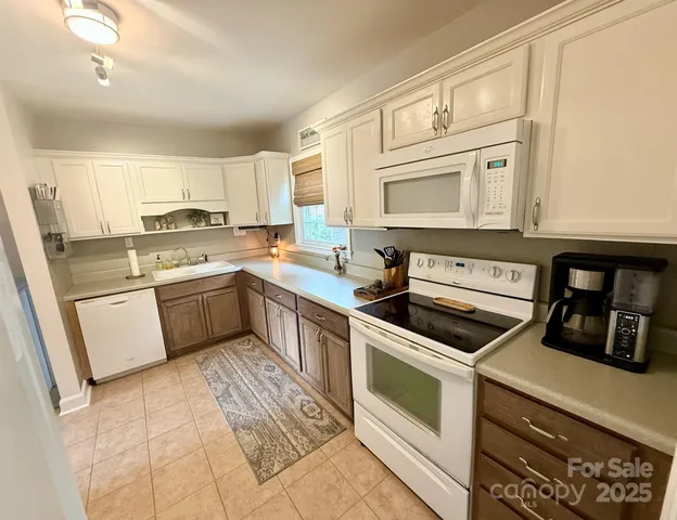 a kitchen with a stove white cabinets and white appliances