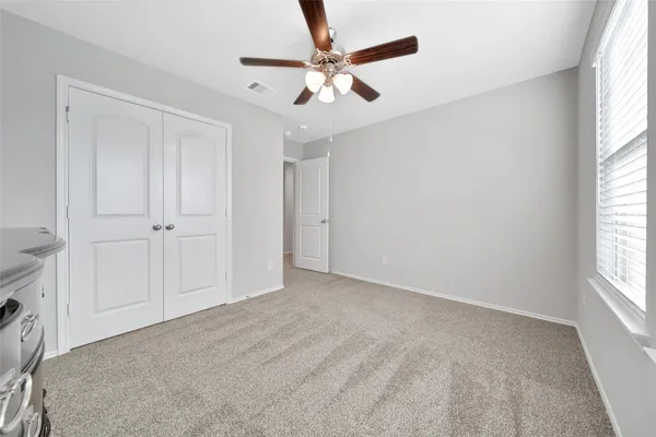 an empty room with windows and fan